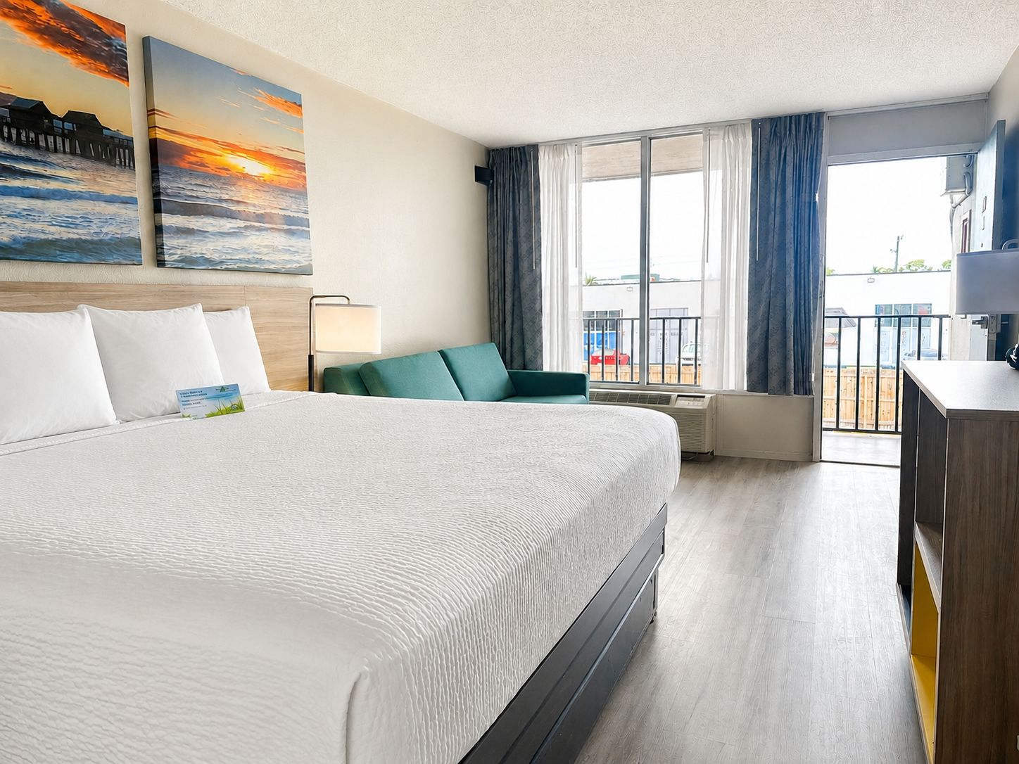 A hotel room with a large bed, a desk, a chair, and a view of the outside.