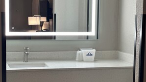 A hotel bathroom with a sink, a mirror, and a Days Inn trash bin.