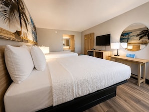 Una camera d'albergo con un letto grande, una scrivania, una TV e uno specchio.