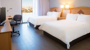 Une chambre d’hôtel avec deux lits, un bureau avec un ordinateur, une chaise et une vue sur la ville.