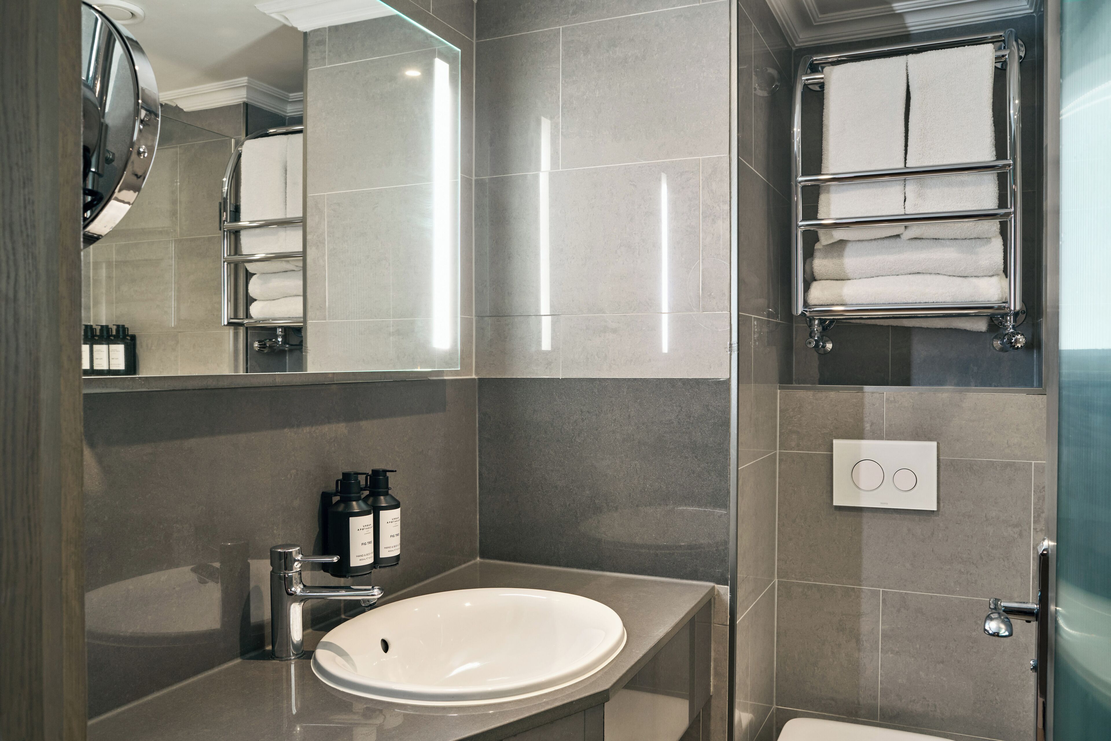 Ein modernes Badezimmer mit Waschbecken, Spiegel, Handtuchhalter und Pflegeprodukten.