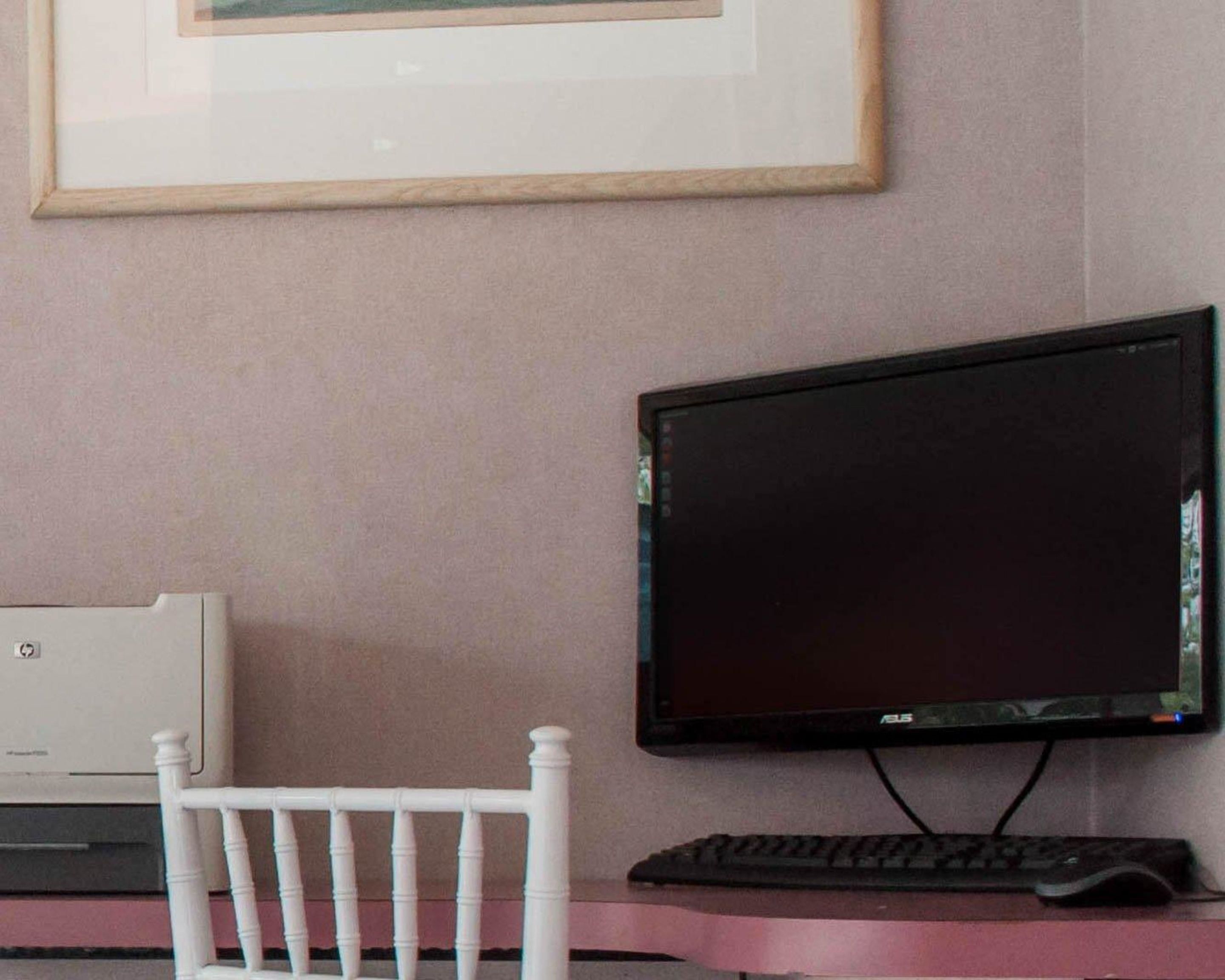 A computer desk with a monitor, keyboard, and a white chair.