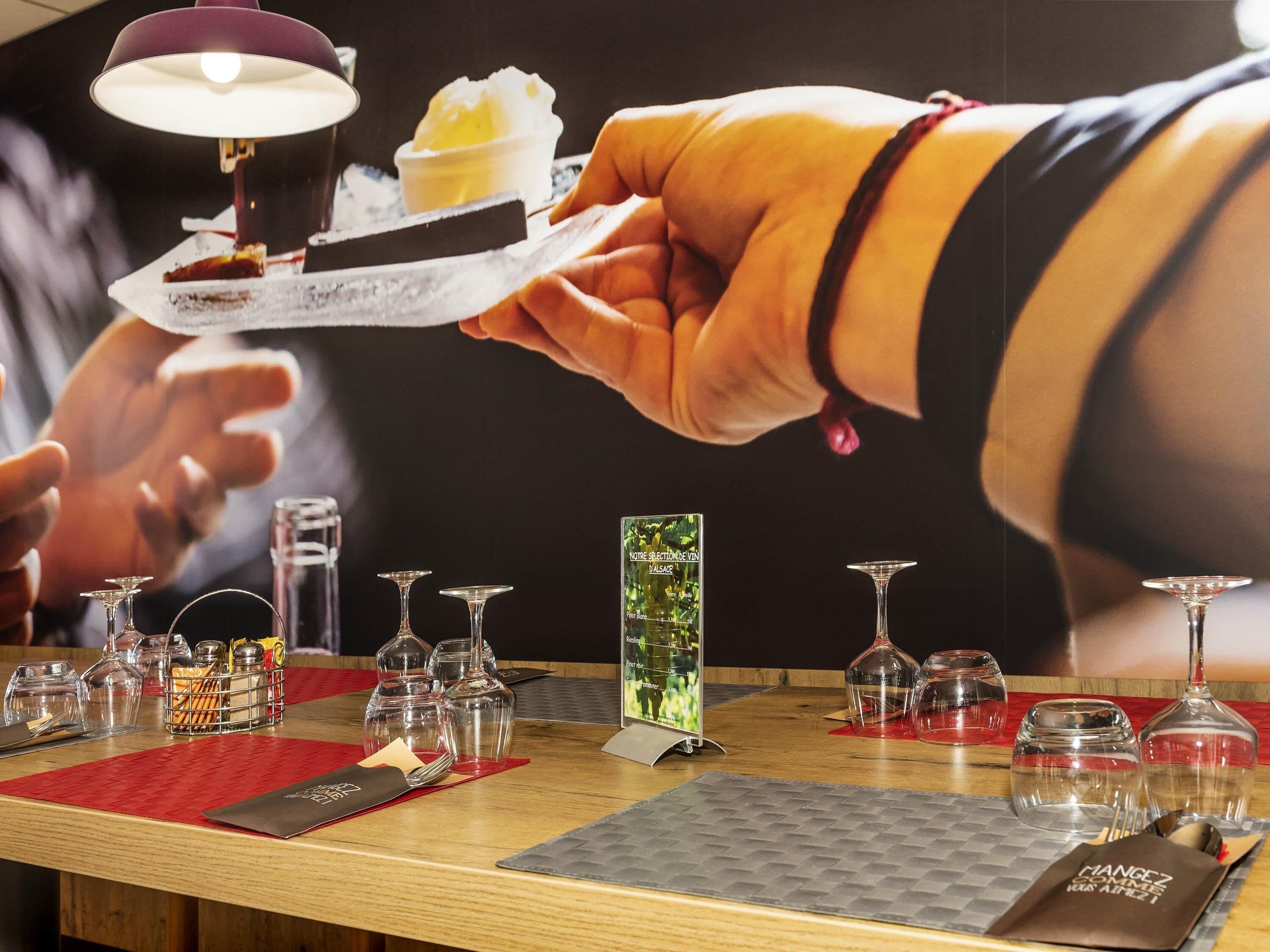 Un ambiente de restaurante con una mesa de madera, copas de vino y un atril para el menú.