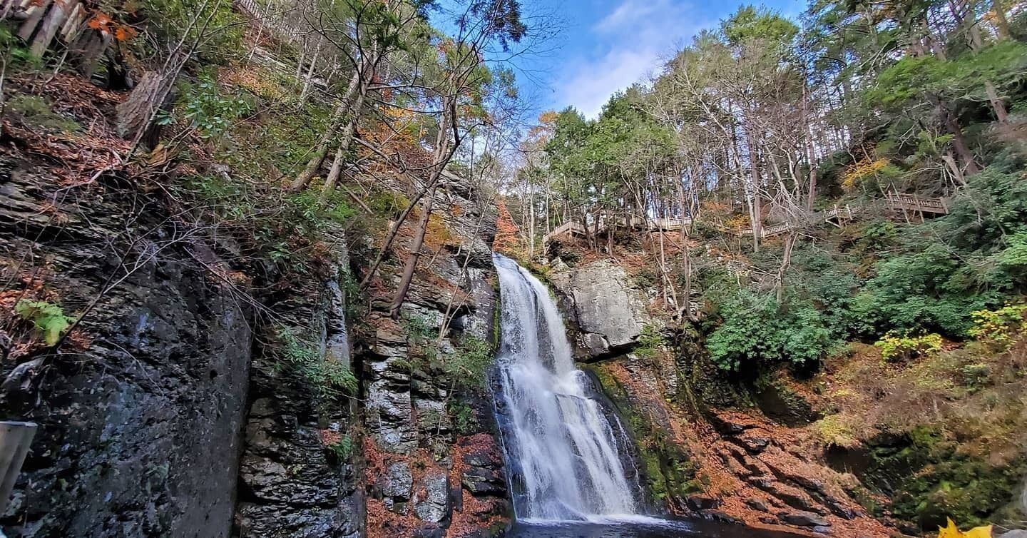 A waterfall surrounded by dense forest and rocky terrain.