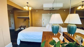 Una habitación de hotel con una cama, dos lámparas, una mesa de madera y una planta.