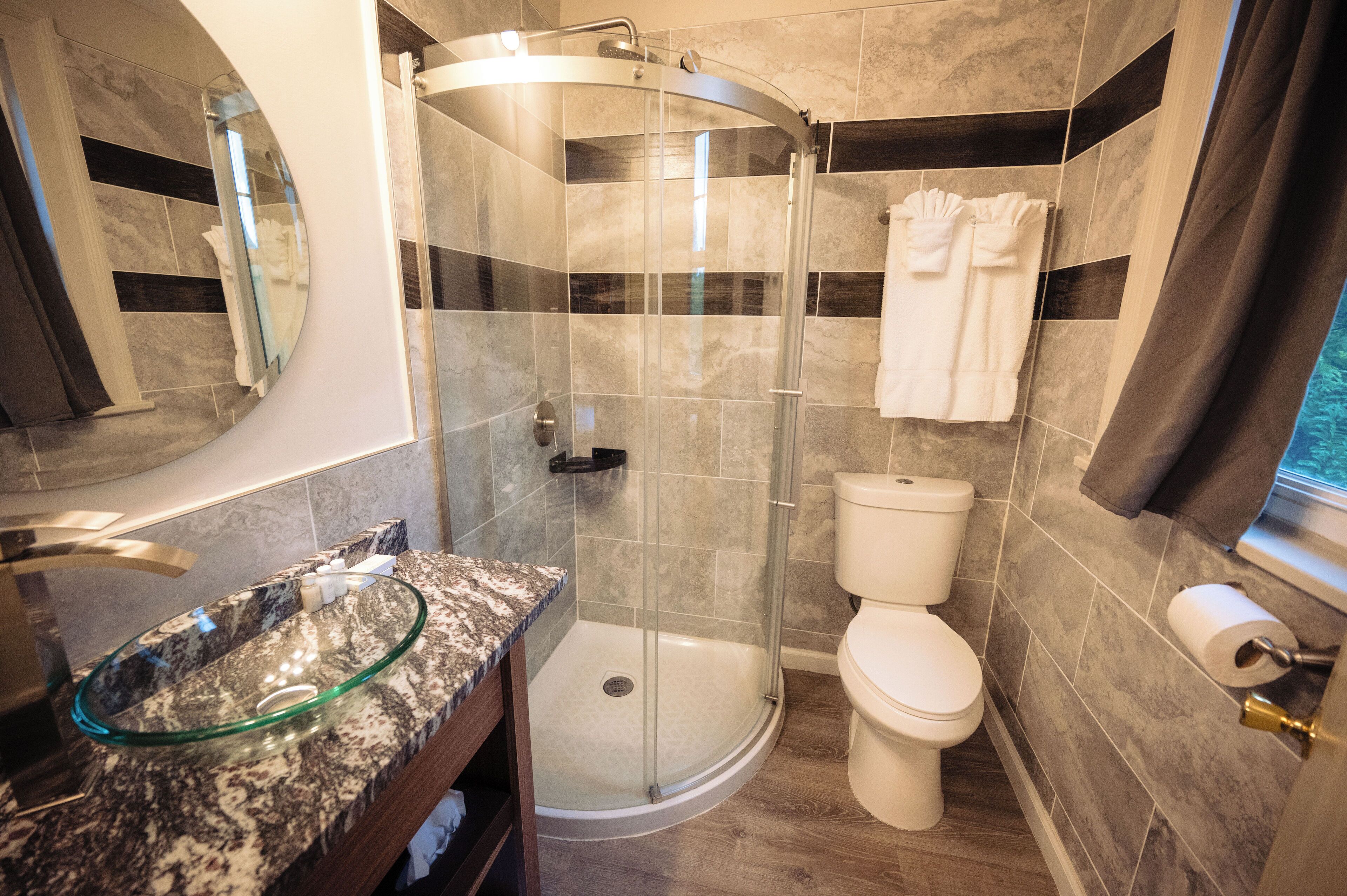 Ein modernes Badezimmer mit einer gläsernen Dusche, einem Marmorwaschbecken und einer Toilette.
