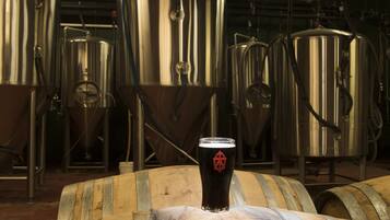 Stainless steel brewing tanks and wooden barrels in a brewery setting.