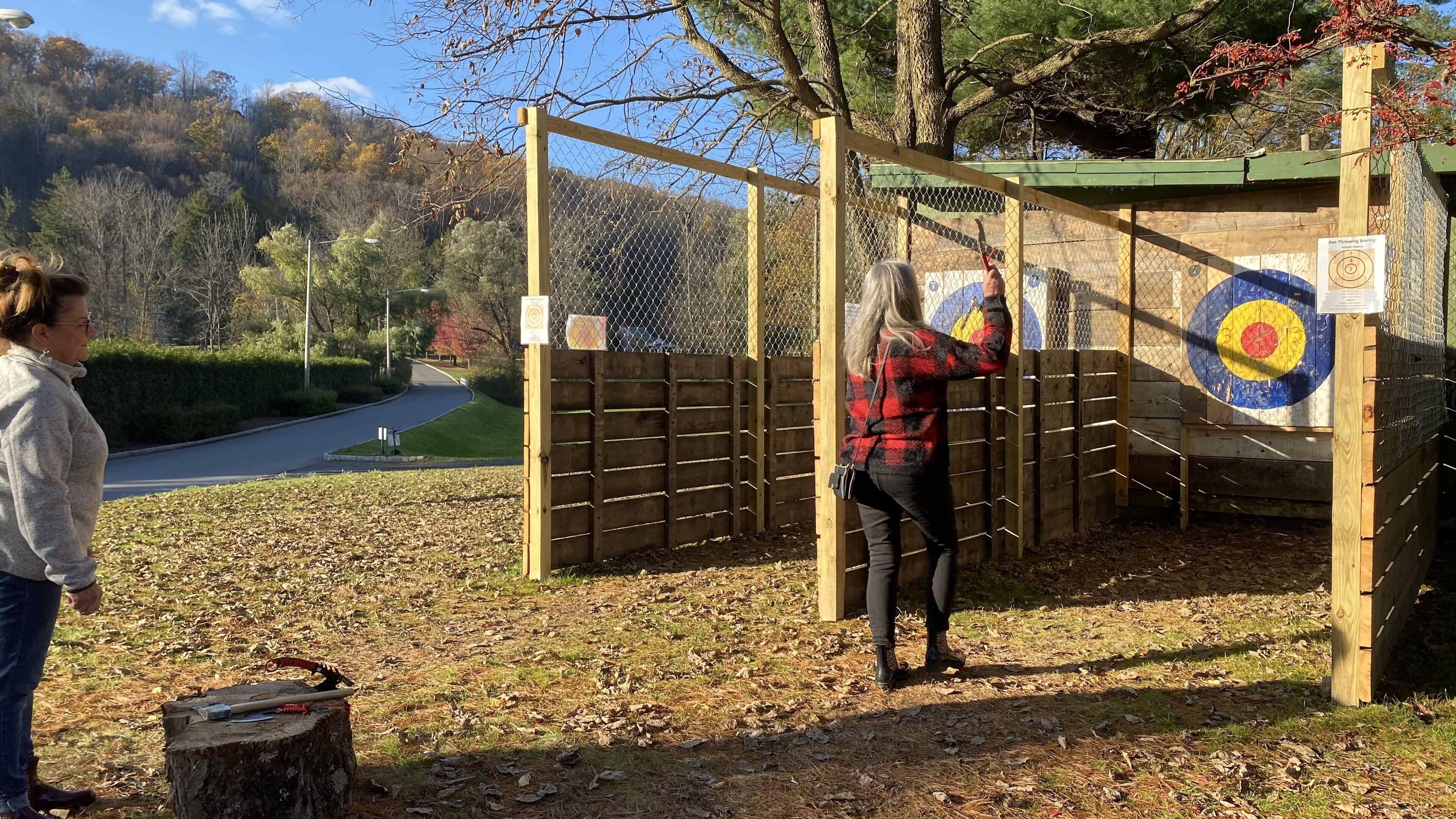 An outdoor archery range with targets, a wooden fence, and a clear sky.