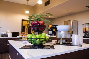 A kitchen counter with a fruit bowl, a coffee machine, and stacked plastic cups.