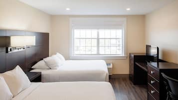 A hotel room with two beds, a TV, a dresser, and a window with blinds.