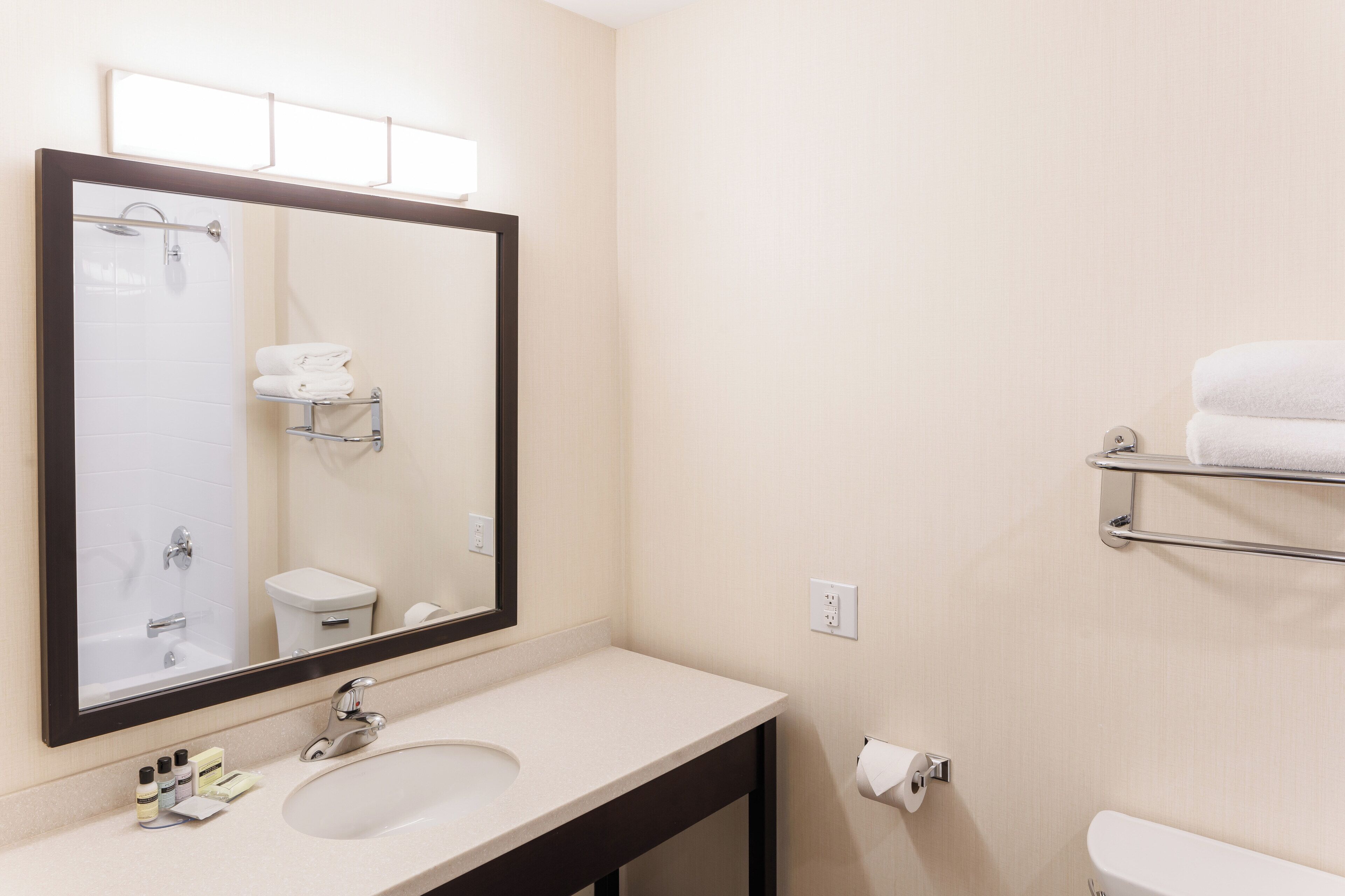 A bathroom with a sink, mirror, towel rack, and toilet.