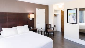 Una habitación de hotel con una cama grande, un escritorio con silla, una mesita y una puerta que da a un baño.