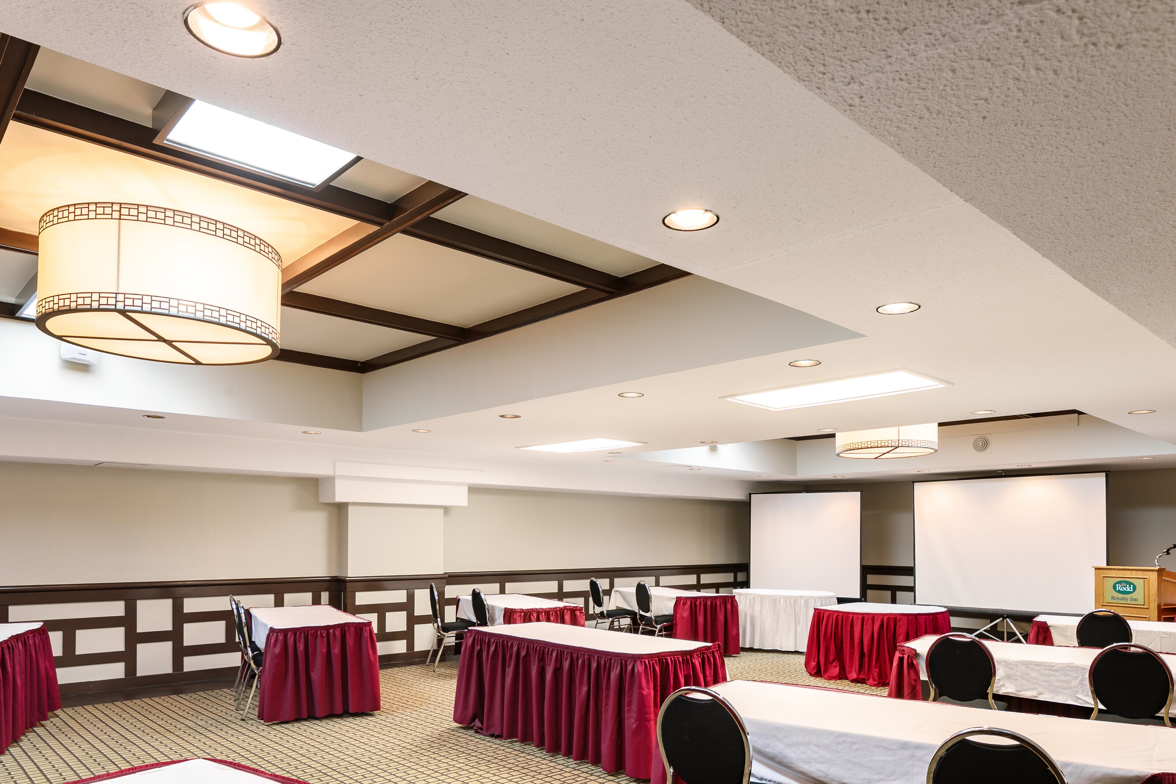 Une salle de conférence équipée de tables, de chaises, d’un écran de projection et d’un pupitre.