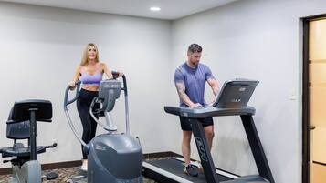 Une salle de sport équipée de tapis de course, d’un vélo elliptique et d’un vélo d’appartement.