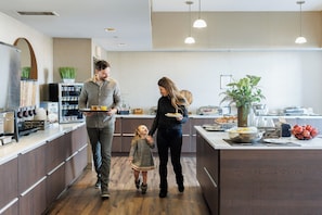 Una cocina moderna con armarios de madera, una isla central con alimentos y un refrigerador con una planta encima.
