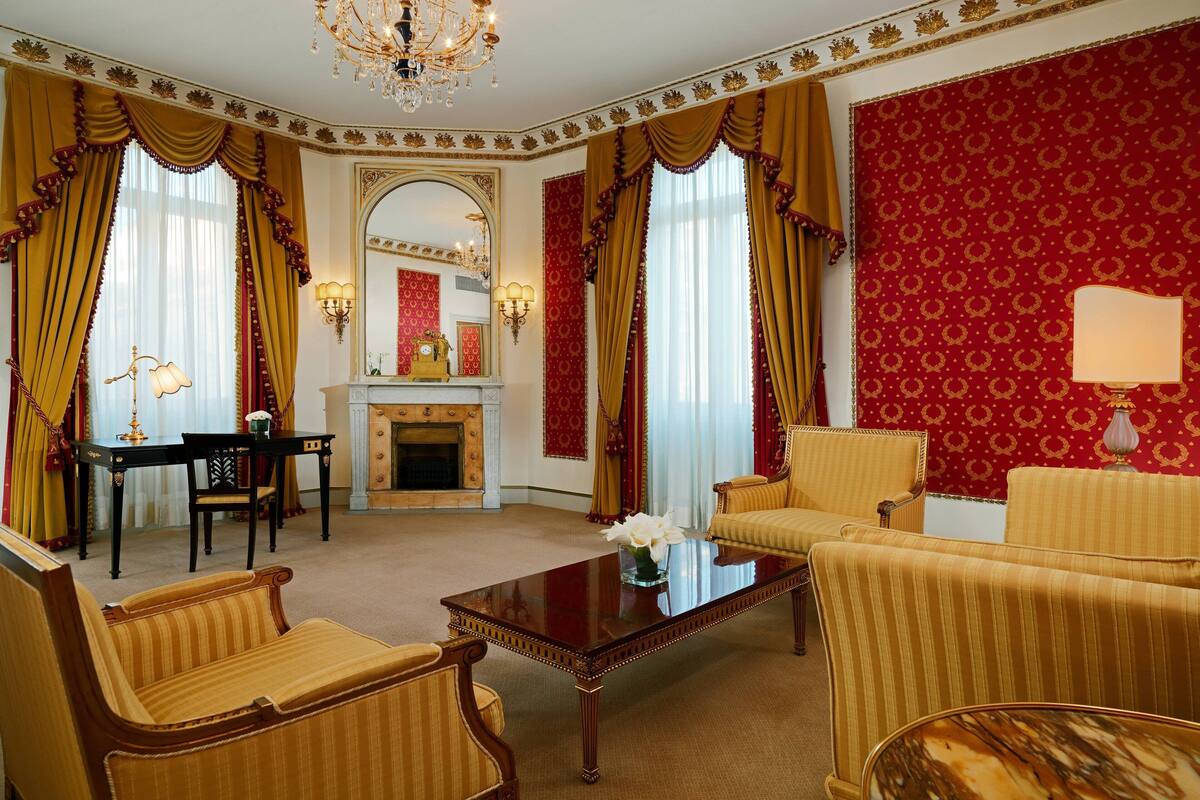 A formal room with a fireplace, a dining table, and two sofas.