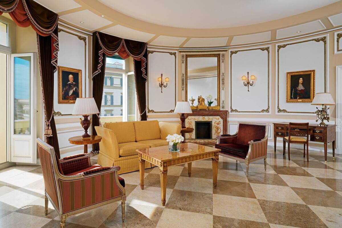 A spacious living room with a checkered floor, a sofa, a coffee table, and a fireplace.