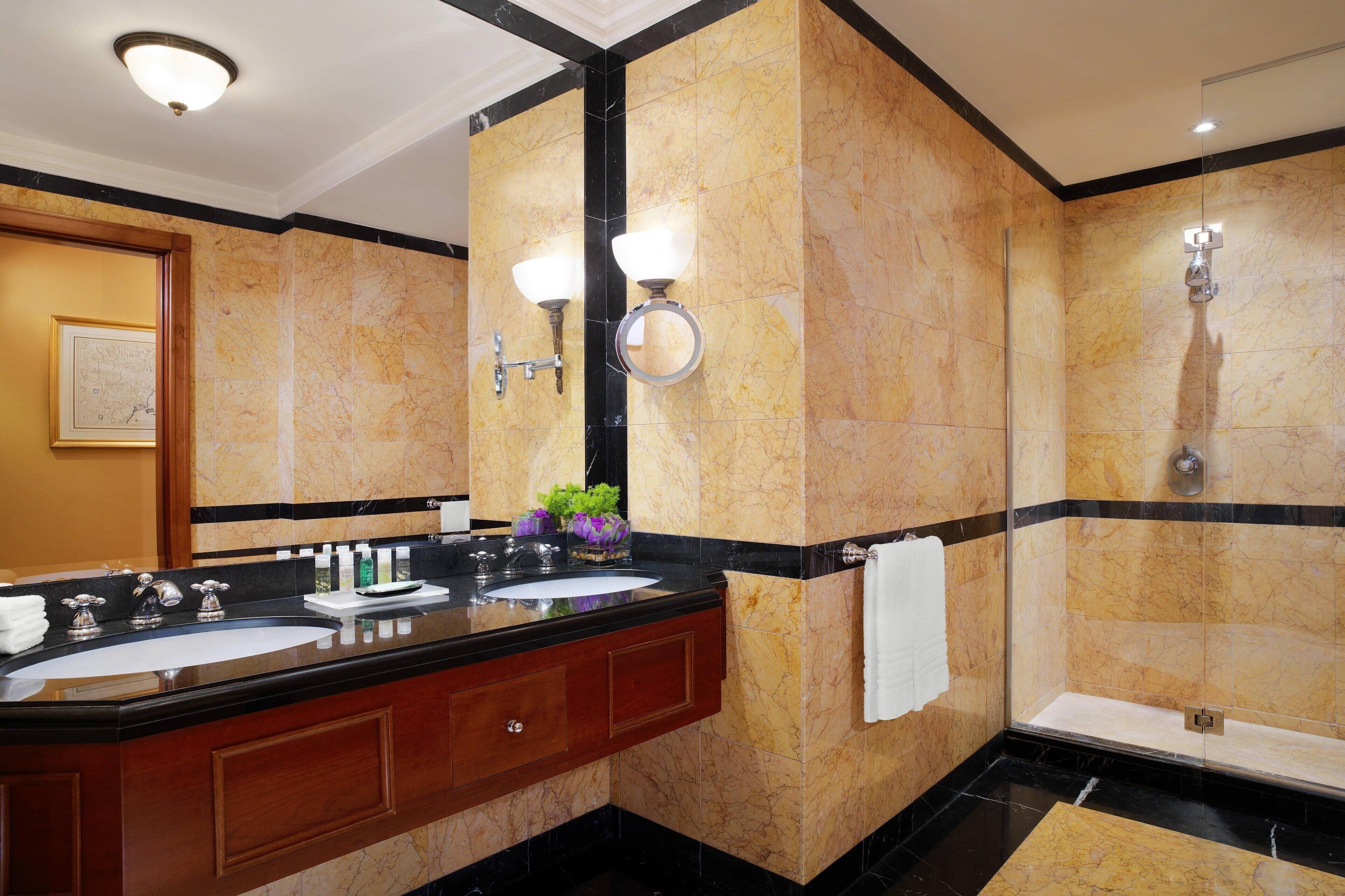 Une salle de bain moderne avec deux lavabos, un grand miroir et une douche à parois de verre.
