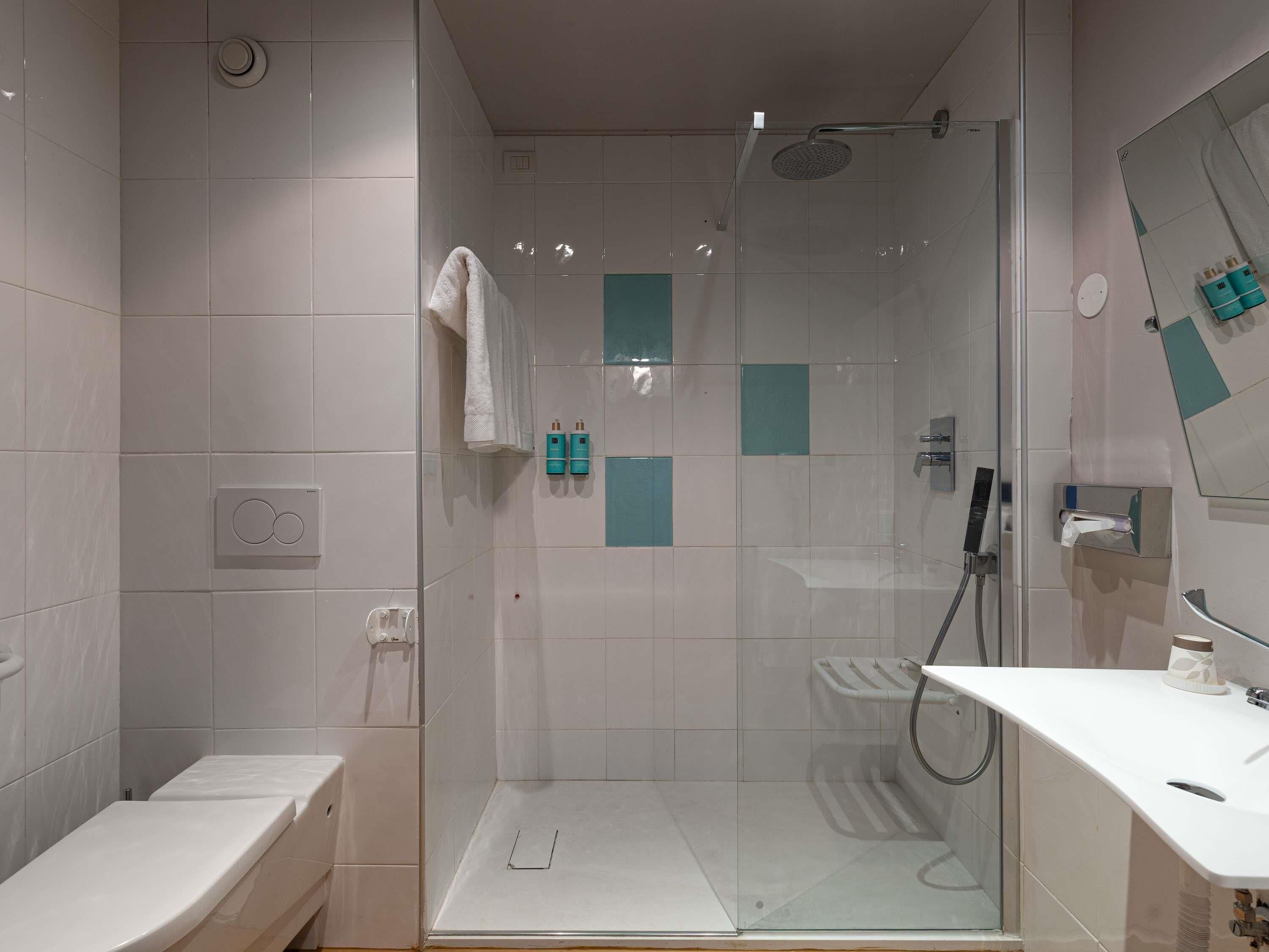 A modern bathroom with a glass-enclosed shower, a white sink, and a toilet.