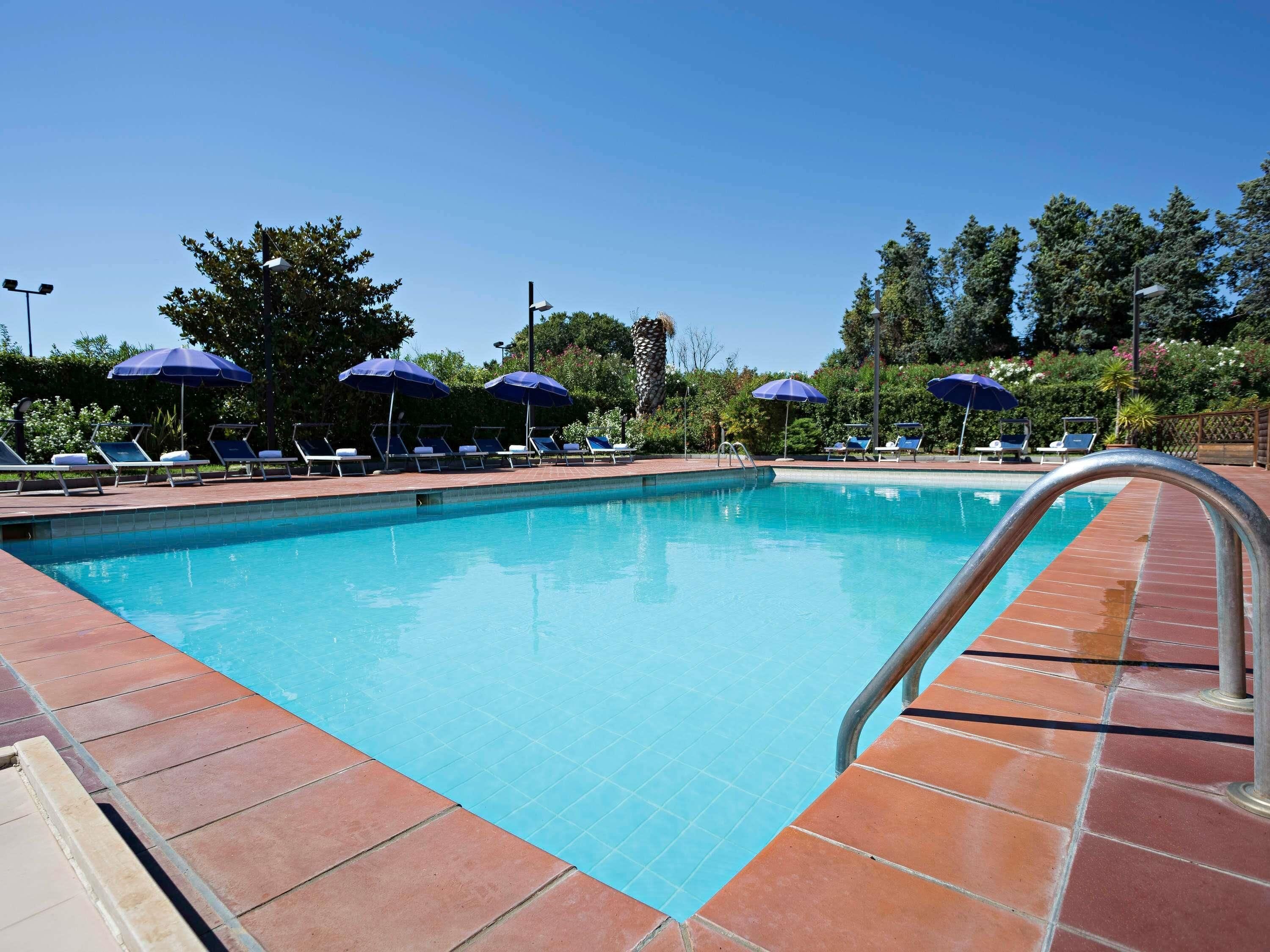 Una piscina al aire libre, sombrillas, tumbonas
