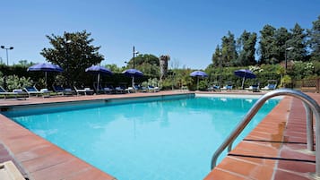 Una piscina al aire libre, sombrillas, tumbonas