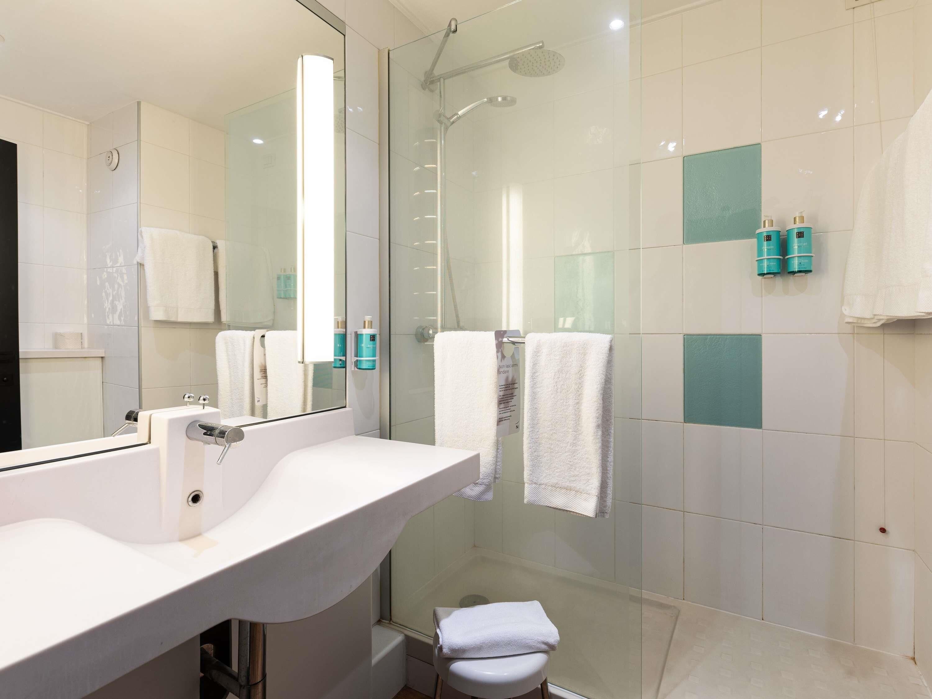 Un bagno moderno con cabina doccia in vetro, un lavandino bianco e un piccolo wc.