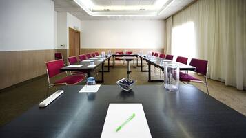 Una sala de conferencias con una larga mesa, sillas rojas y una pizarra.