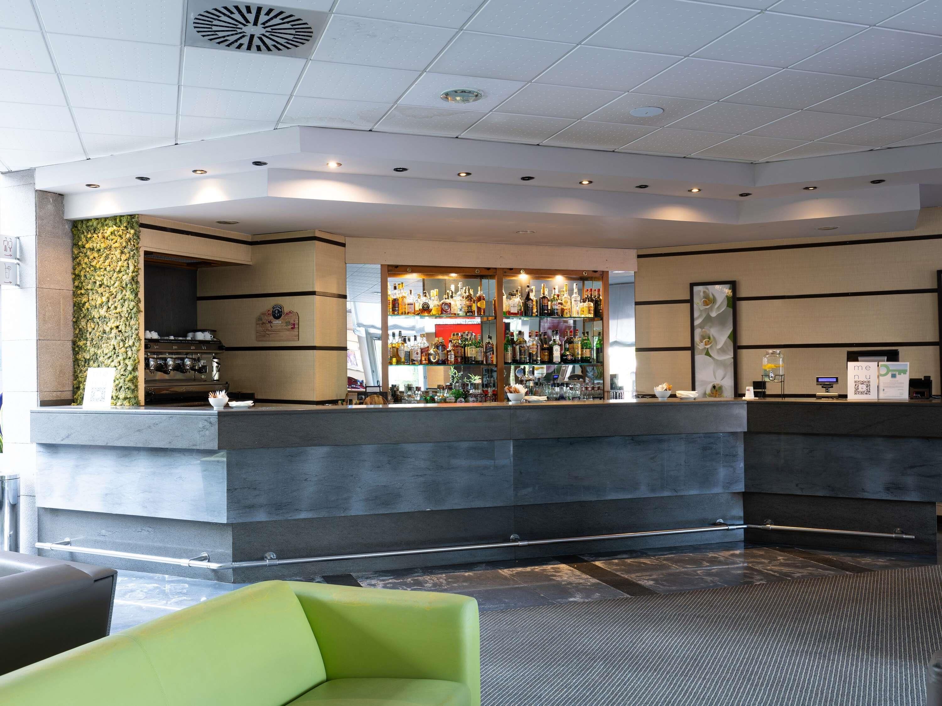 Eine Bar mit einer Theke, Flaschenregalen und einer Kaffeemaschine.