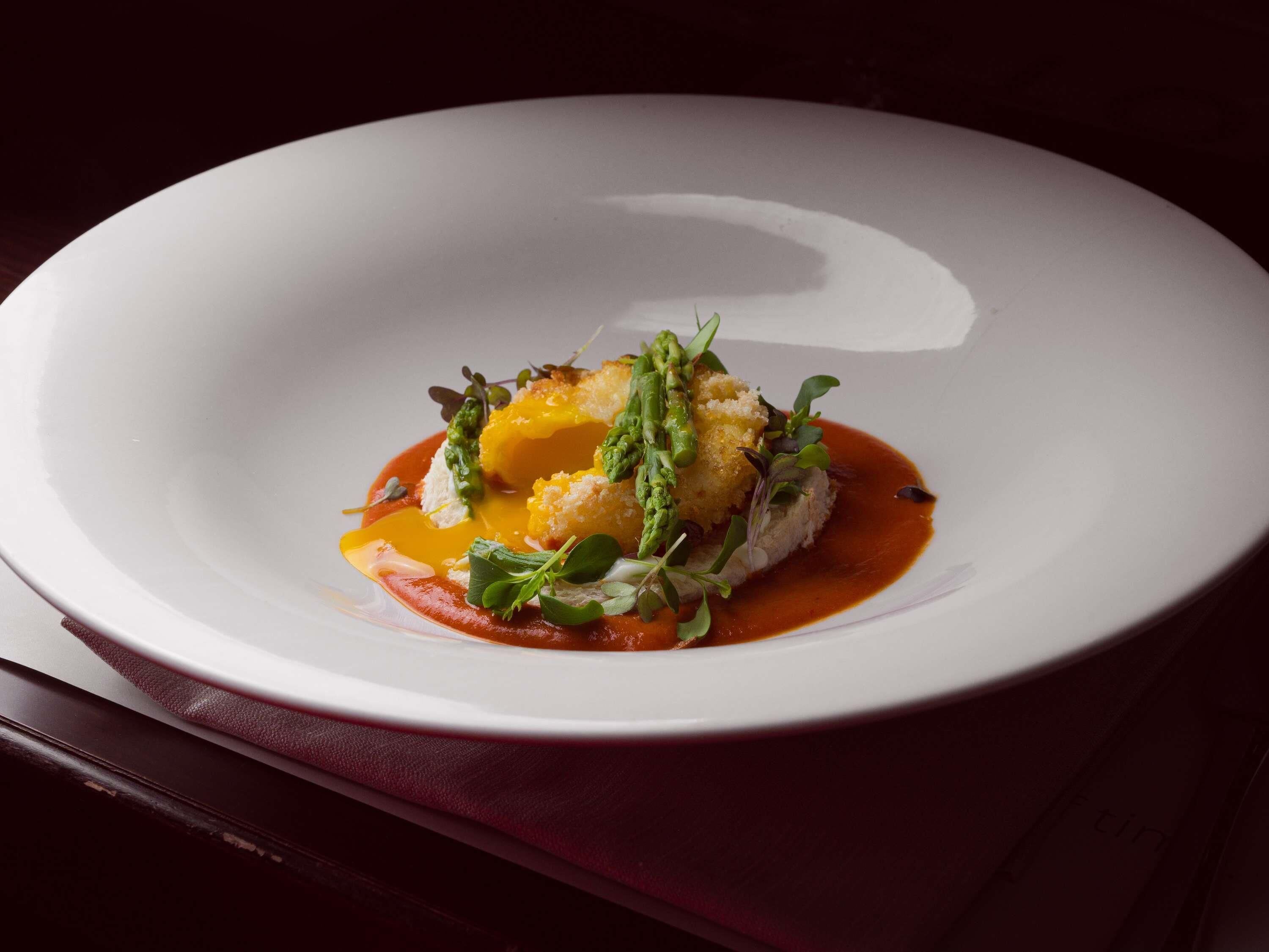 A white plate with a dish on a dark table.