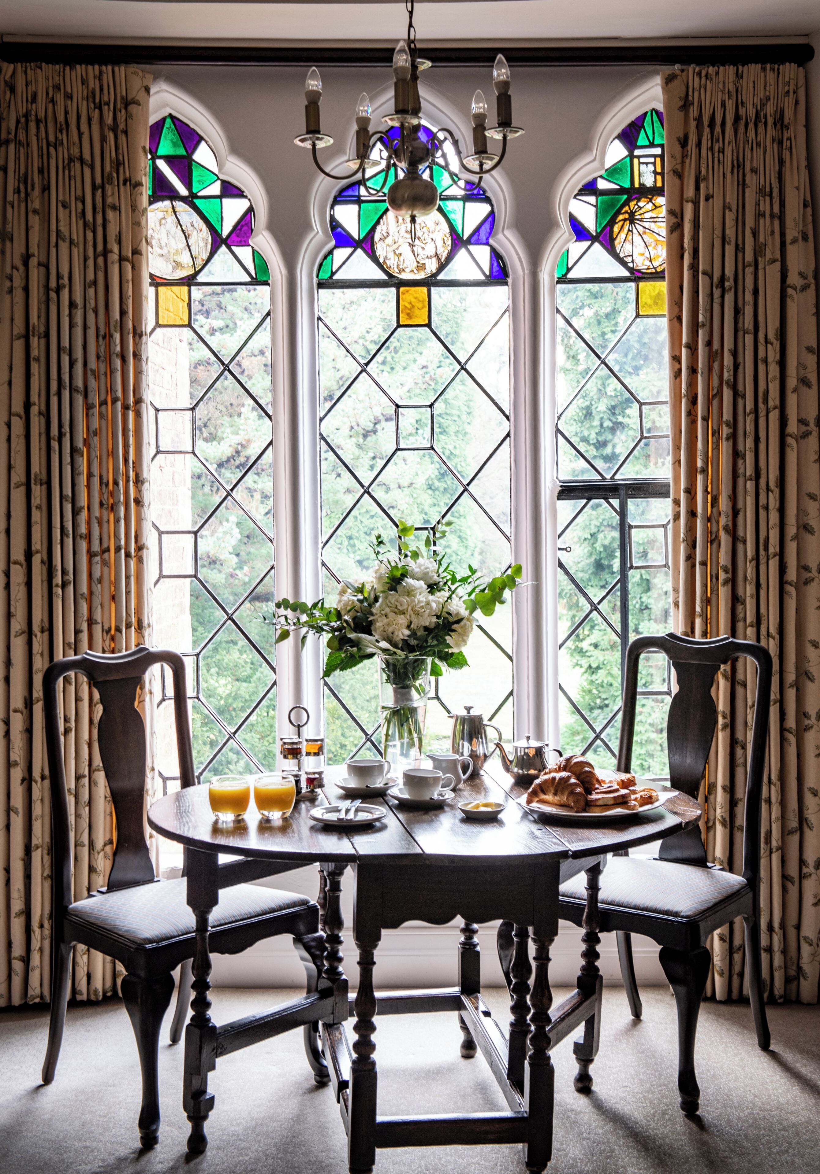Une table à manger avec des chaises, un vase de fleurs et des aliments pour le petit-déjeuner.