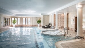 An indoor swimming pool with a hot tub, lounge chairs, and potted plants. - New Hall Hotel & Spa (Sutton Coldfield)