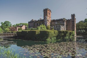 A historic building with a tower, surrounded by a moat and lily pads. - New Hall Hotel & Spa (Sutton Coldfield)
