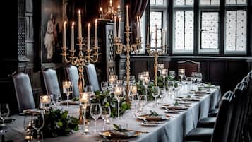 Una larga mesa de comedor dispuesta para una comida formal, con velas, copas y platos.