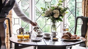 A breakfast setting with a table, tea set, croissants, and a flower arrangement. - New Hall Hotel & Spa (Sutton Coldfield)