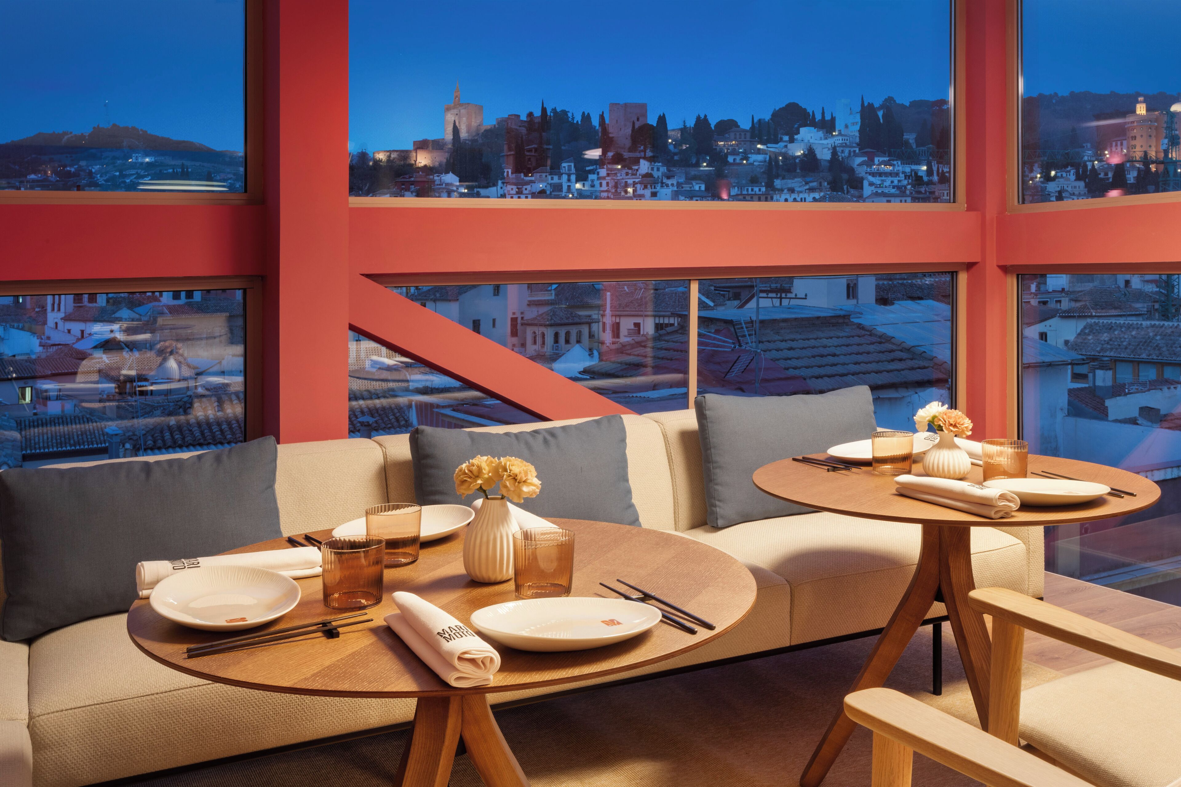 A modern dining area with a sofa and a round table, both with wooden legs.