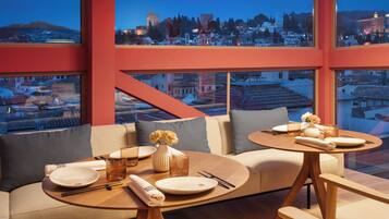 A modern dining area with a sofa and a round table, both with wooden legs.
