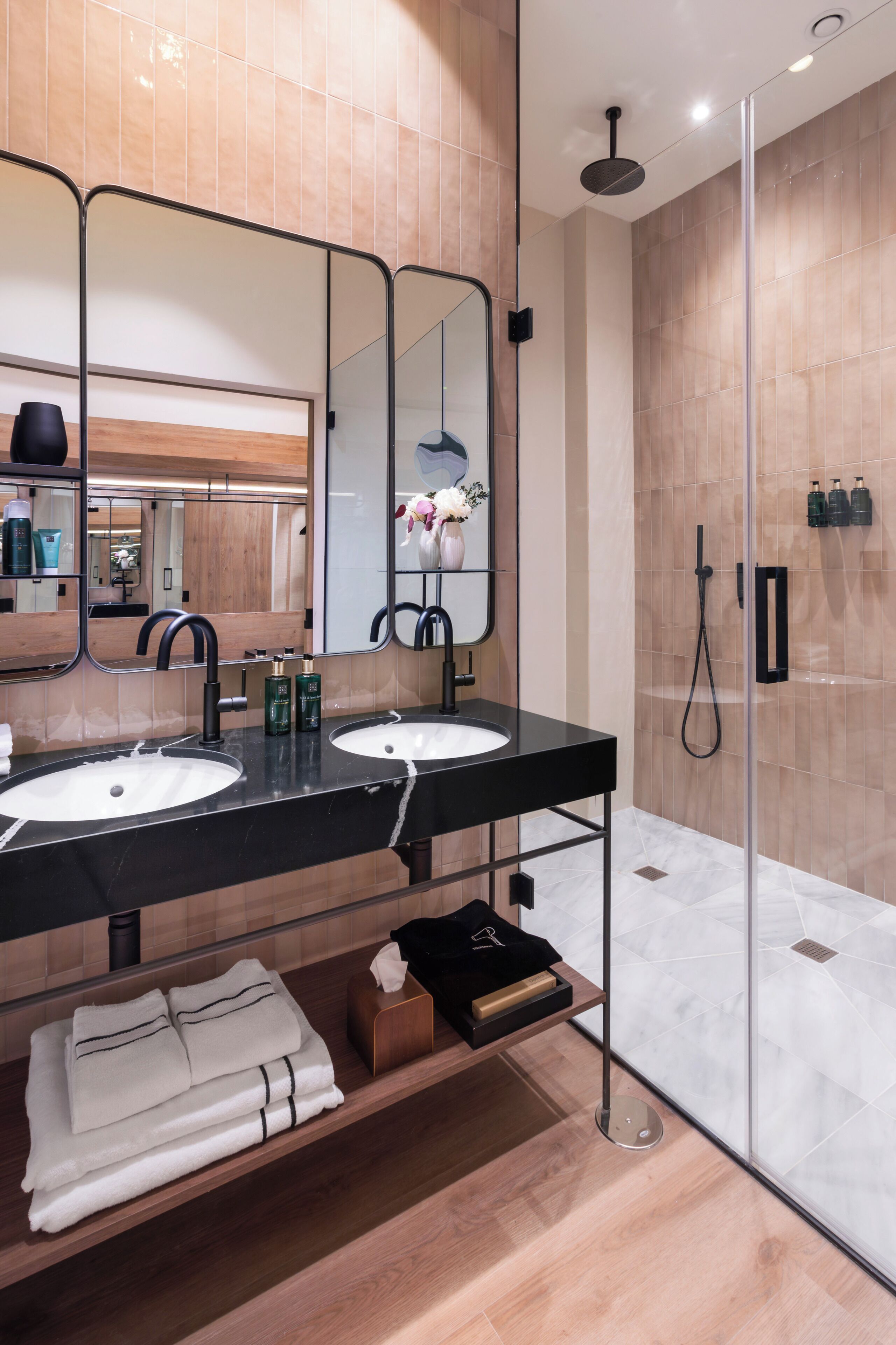 A modern bathroom with two sinks, a large mirror, and a glass-enclosed shower area.