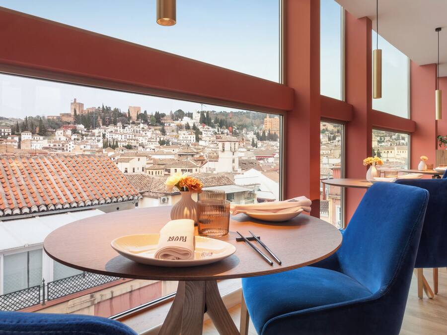 Comedor con una mesa para dos, vistas a la ciudad y sillas azules.