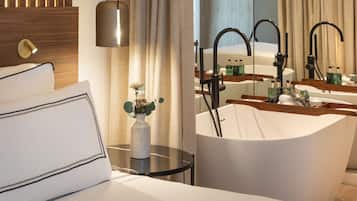 A modern bathroom with a large sink, a mirror, and a small table with a vase.