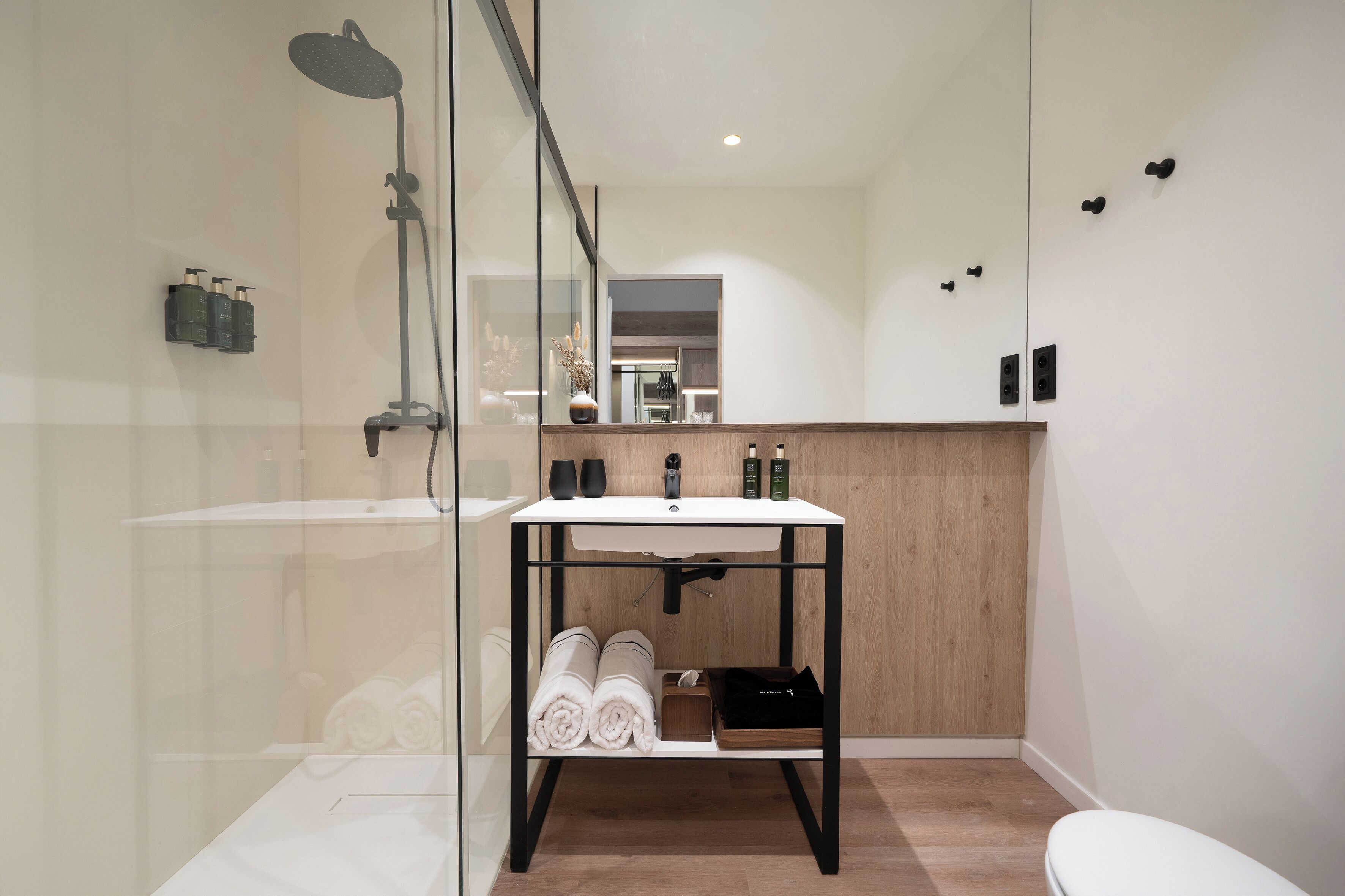 A modern bathroom with a glass shower enclosure, a wooden vanity with a sink, and a toilet.