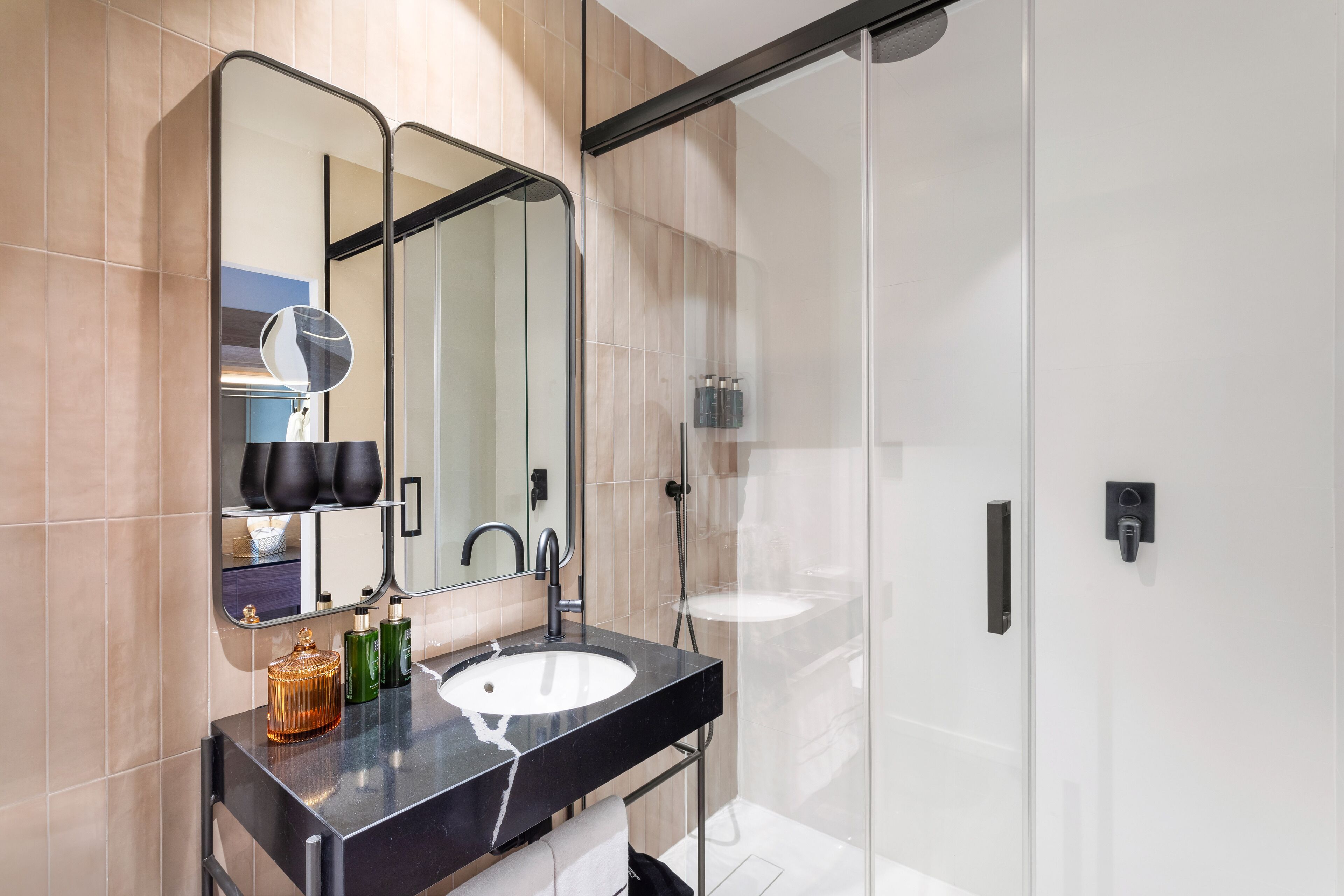 A modern bathroom with a black countertop, a white sink, and a large mirror.