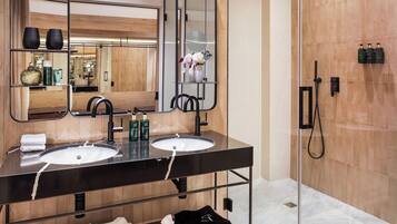 Un baño moderno con dos lavamanos, un espejo grande y una cabina de ducha de vidrio.