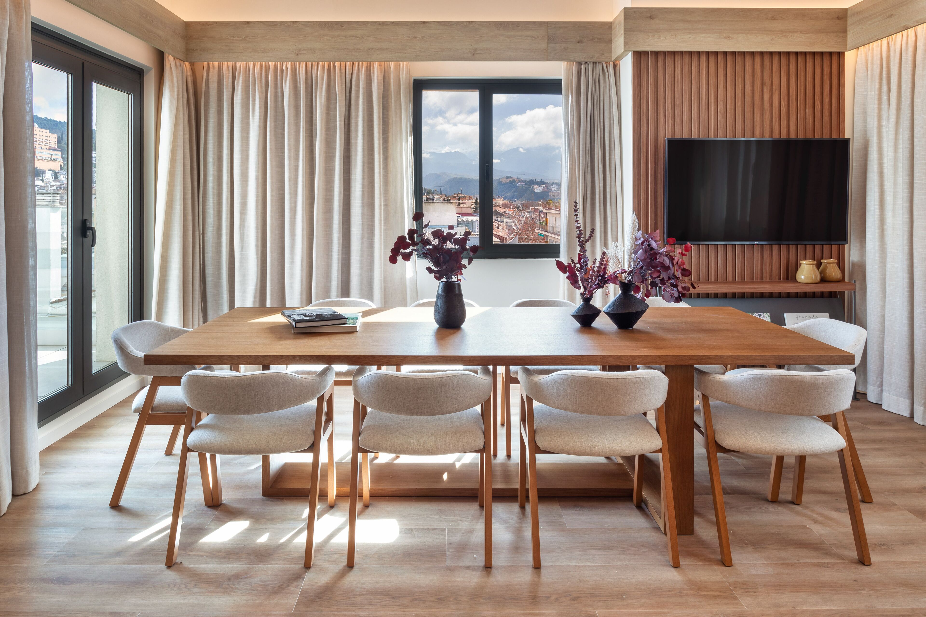 Un'area pranzo moderna con un tavolo in legno, sei sedie e un'ampia finestra con tende.