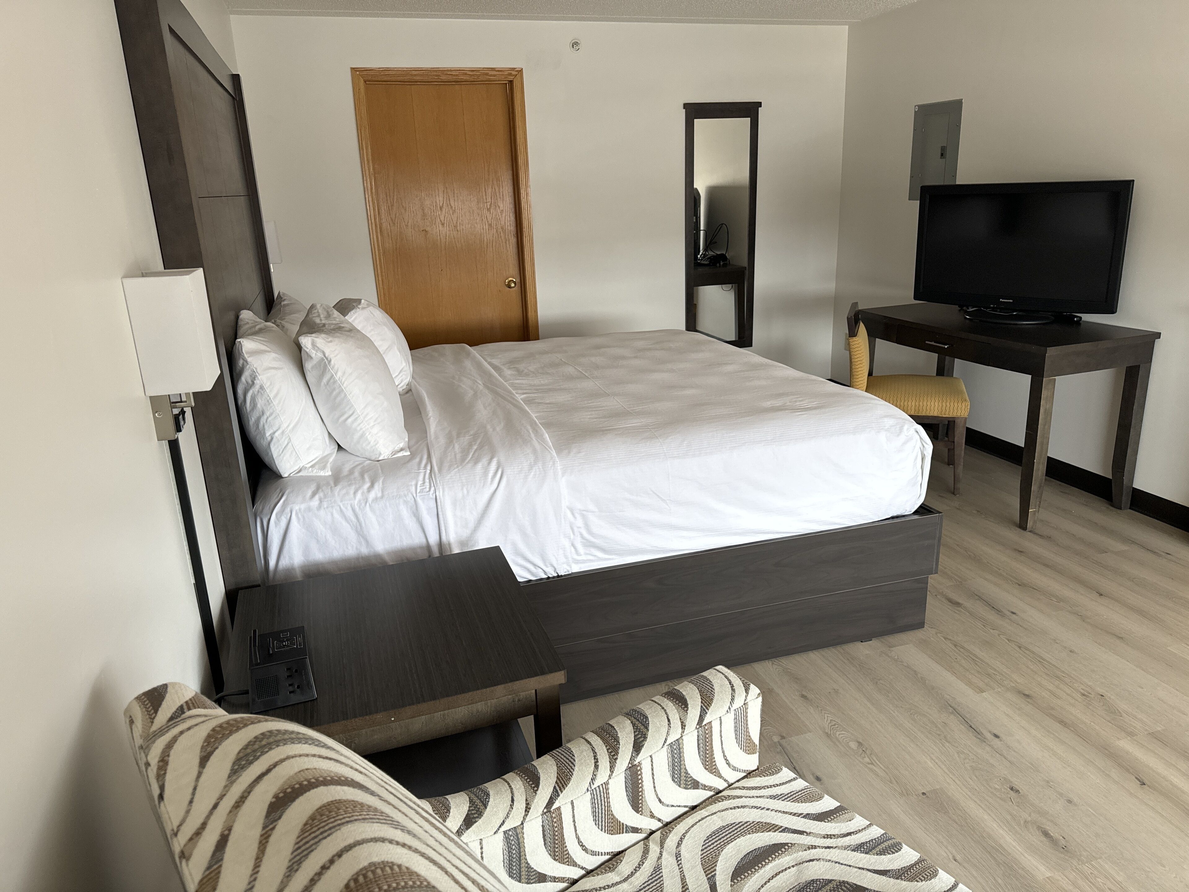 A hotel room with a bed, a desk, a television, and a chair.