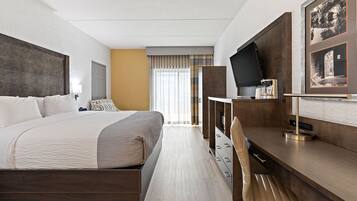 A hotel room with a large bed, a desk with a coffee maker, a television, and a framed picture on the wall.