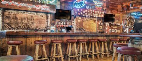 A bar with wooden stools and a neon sign.