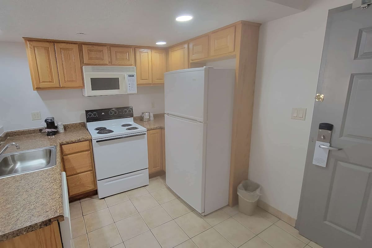 A compact kitchen with a stove, microwave, refrigerator, and a sink.