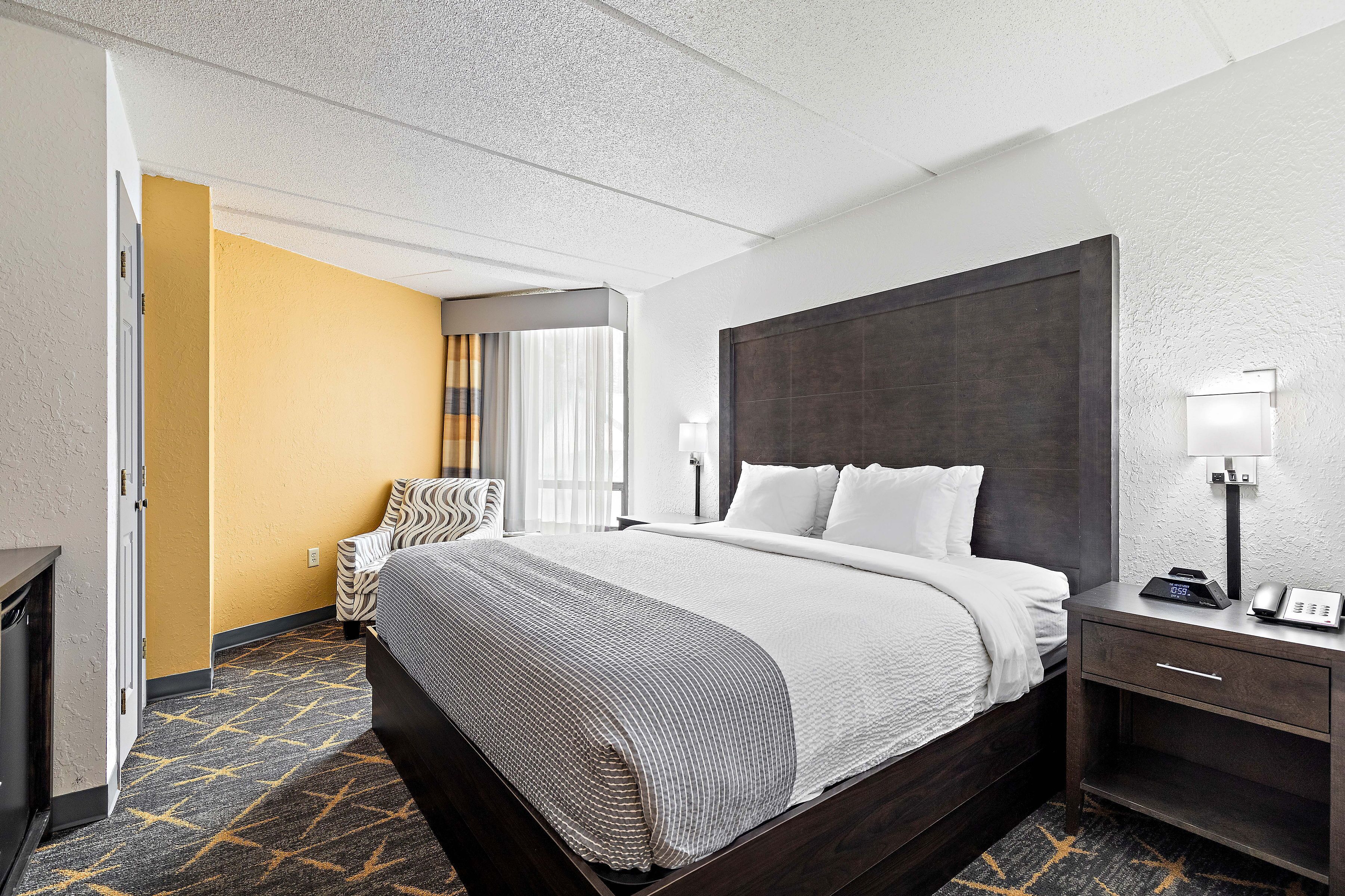 A hotel room with a large bed, bedside tables, a wardrobe, and a view of the hallway.