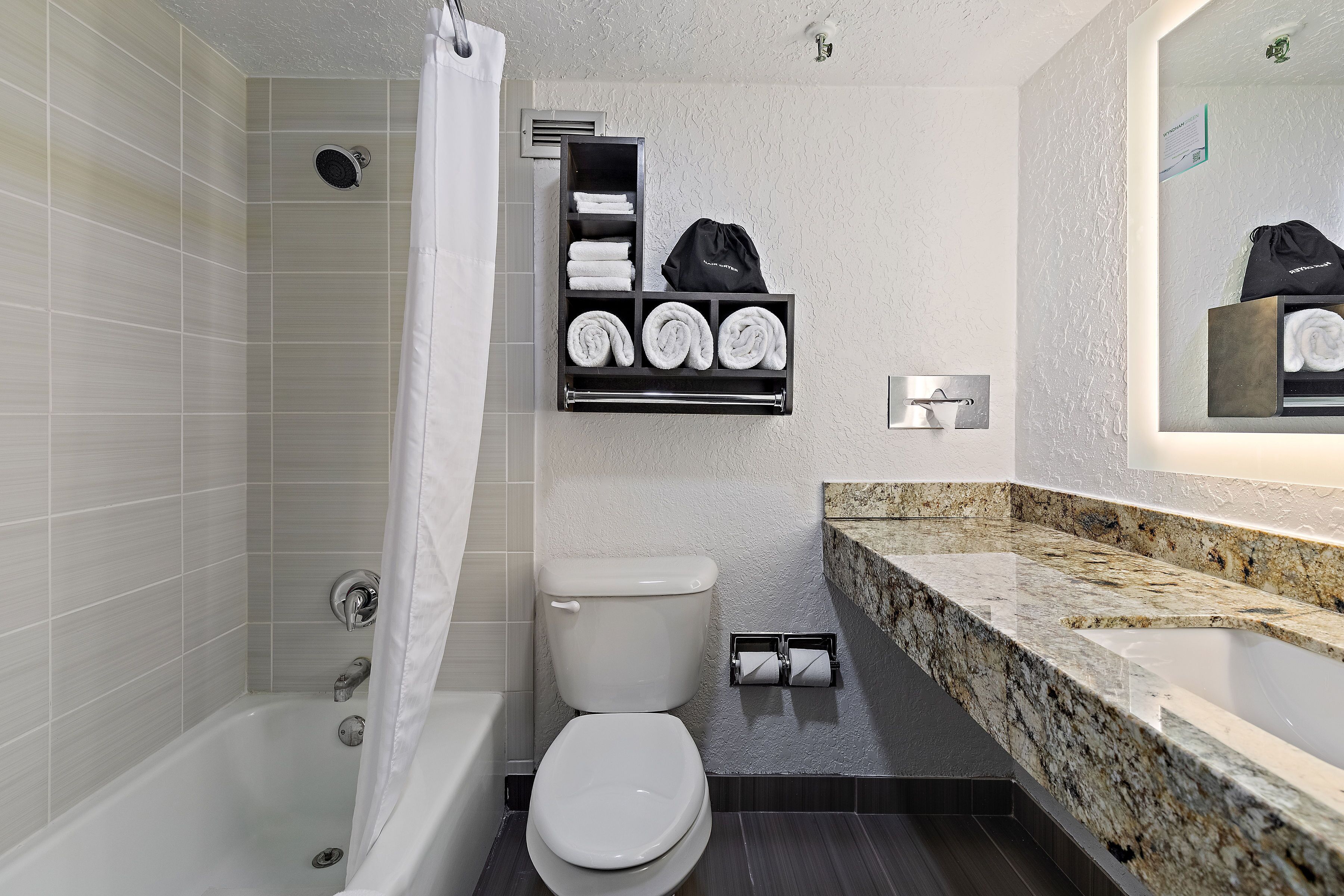 A modern bathroom with a bathtub, toilet, and a marble countertop.