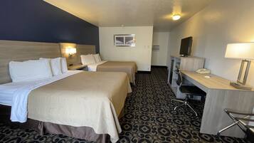 A hotel room with two beds, a desk, a chair, a desk lamp, a telephone, and a television.